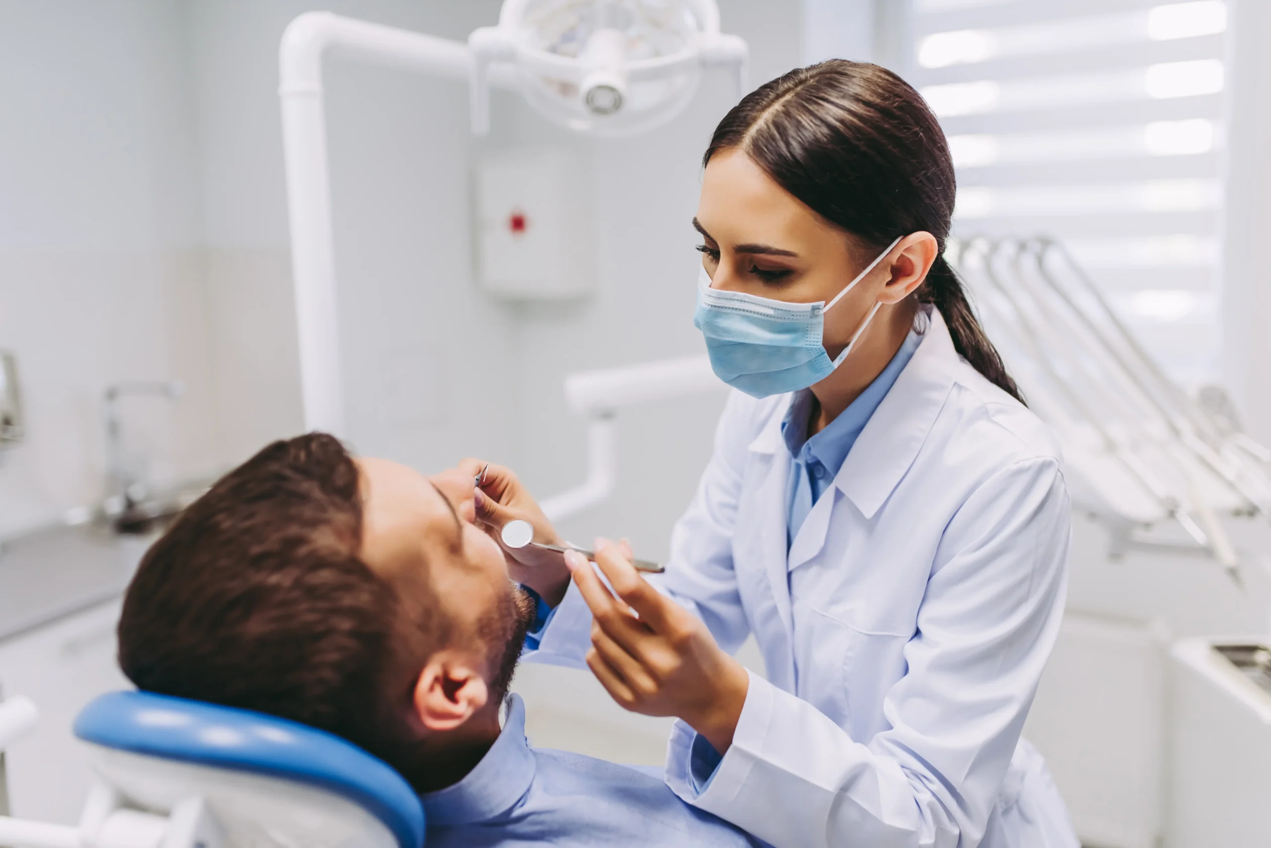 female-dentist-checking-patient-teeth-with-mirror-modern-dental-clinic